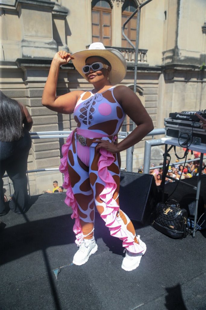 Gaby Amarantos de macacão estilizado branco e rosa, chapéu e óculos escuros