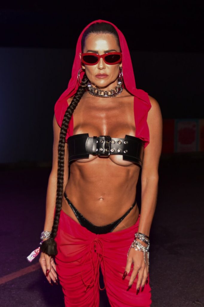 Deborah Secco de calça vermelha, gorro vermelho, top de cinto preto, calcinha preta à mostra, barriga de fora e óculos escuros