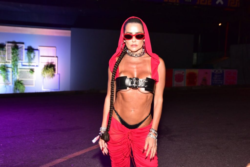 Deborah Secco de calça vermelha, gorro vermelho, top de cinto preto, calcinha preta à mostra, barriga de fora e óculos escuros