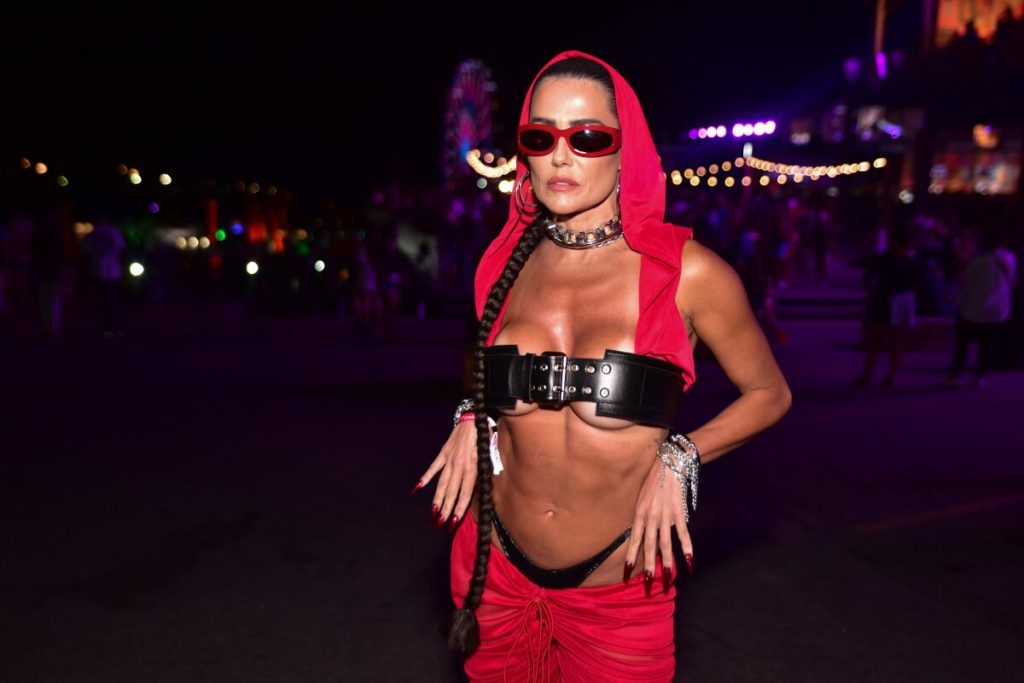 Deborah Secco de calça vermelha, gorro vermelho, top de cinto preto, calcinha preta à mostra, barriga de fora e óculos escuros