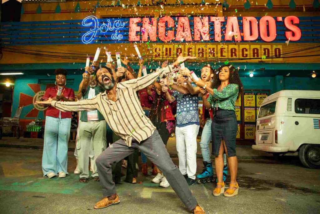 Eraldo (Luís Miranda) sendo surpreendido por todos os funcionários estourando confete em cima dele em cena da série "Encantado's"