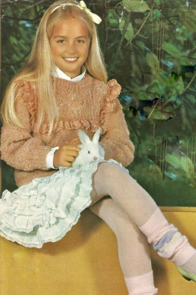 Angélica segurando um coelho, sentada, na infância