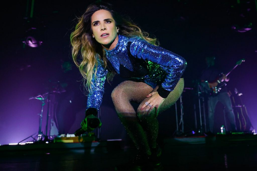 Wanessa no palco de body azul agachada