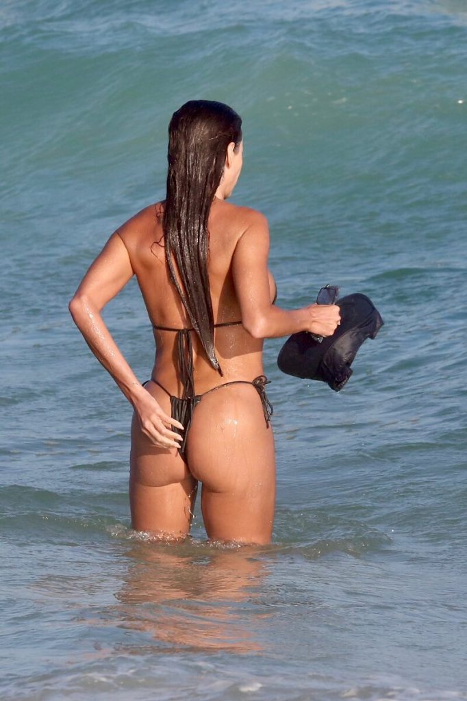 Deborah Secco ajeitando biquíni fio dental verde musgo na praia 