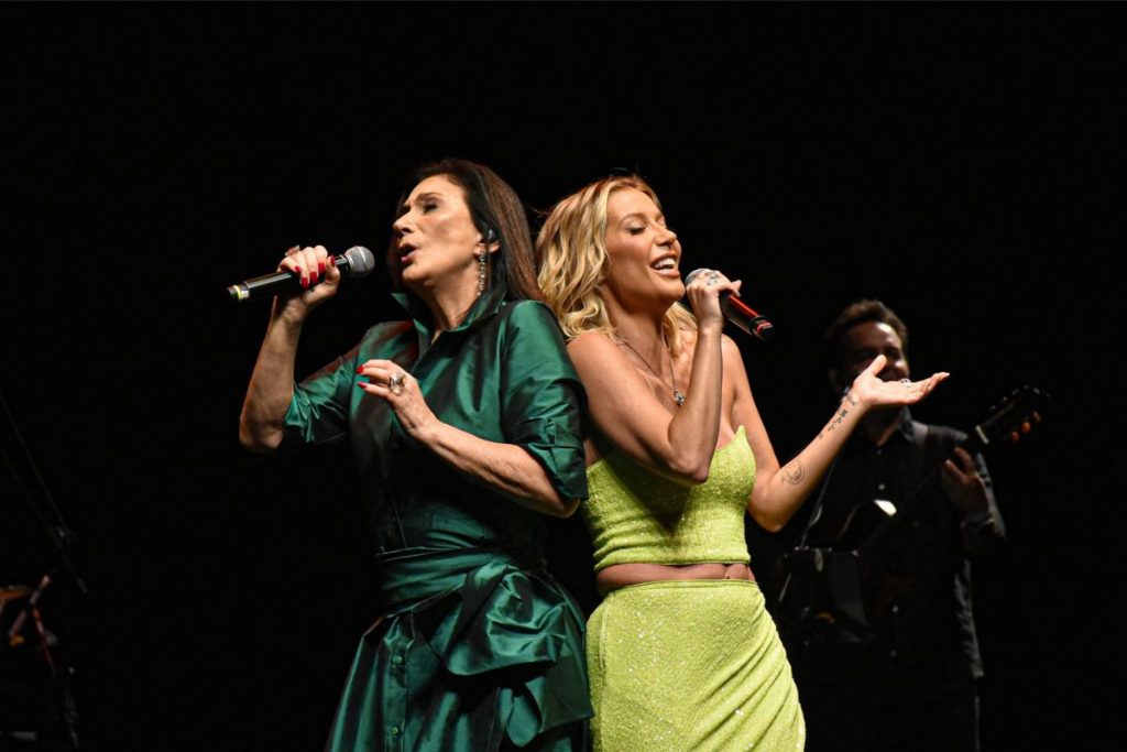 Luiza e Zizi Possi cantam de costas em palco