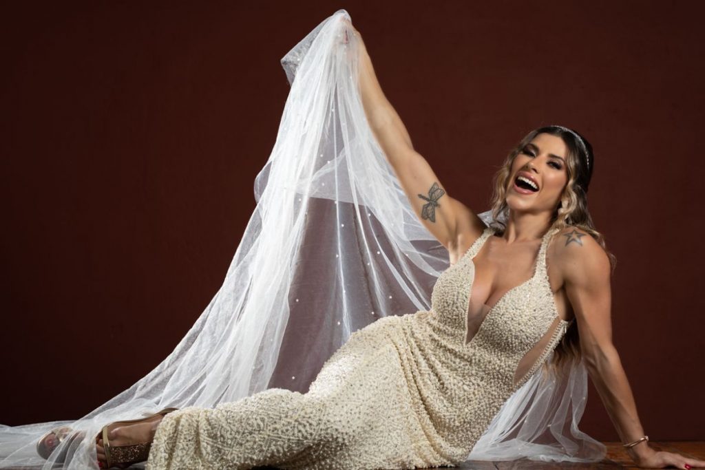 Ana Paula Minerato com vestido de noiva dourado, levantando o véu