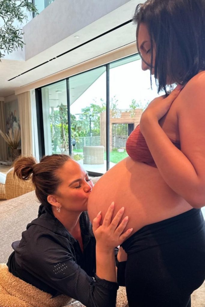 Chrissy Teigen beija barriga de aluguel