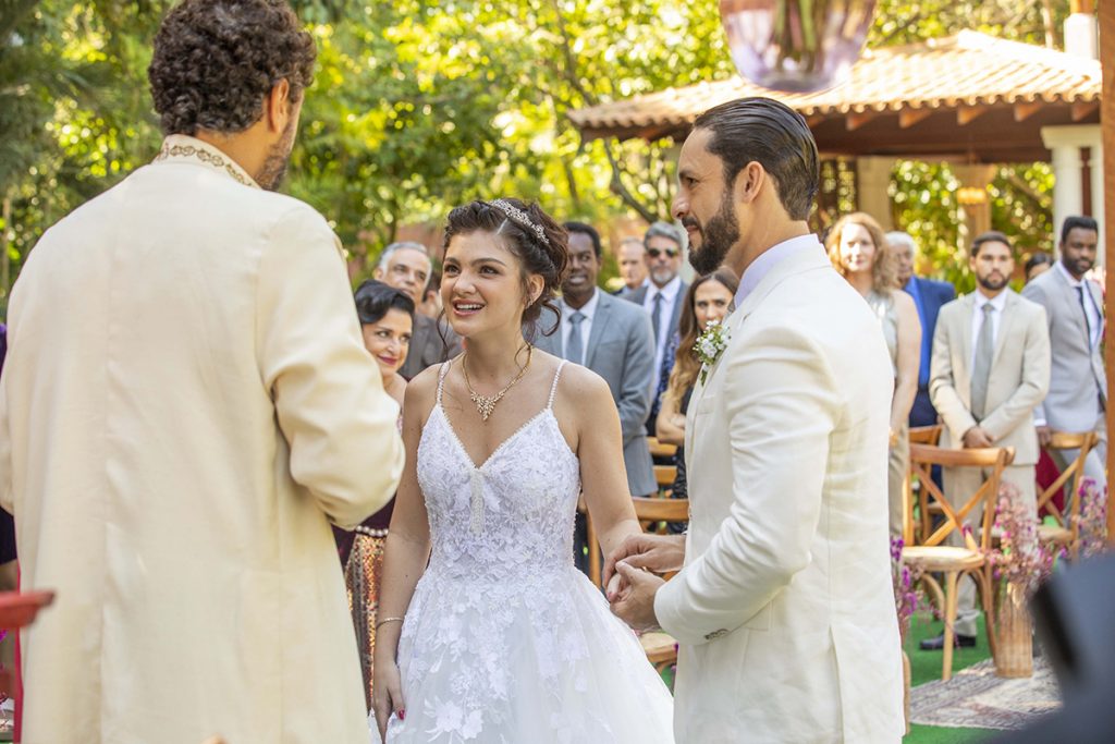 A noiva usa um vestido bem fluido e cabelos presos para a ocasião