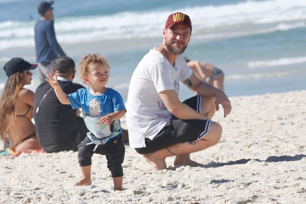 Emílio Dantas observa o filho andando, na praia