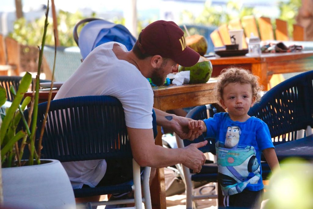 Emílio Dantas senta no quiosque com um dos gêmeos