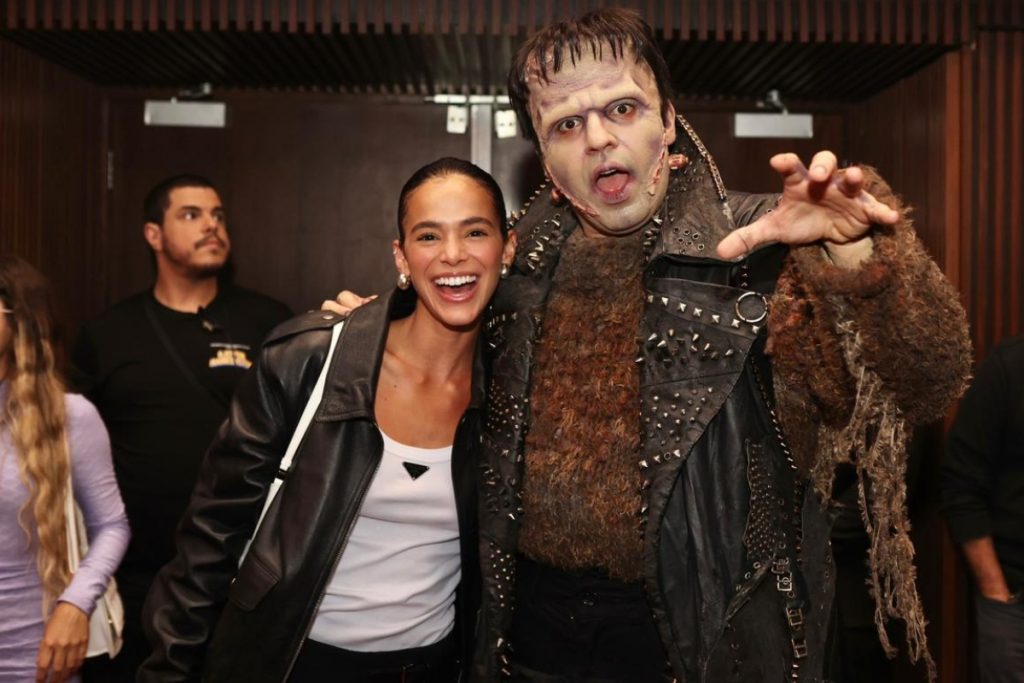 Bruna Marquezine de jaqueta preta, abraçada ao Frankenstein