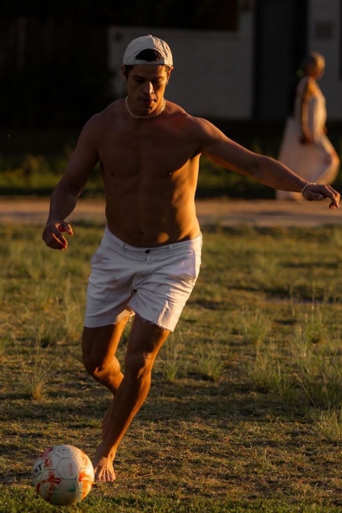José Loreto sem camisa, de calção branco, jogando bola 