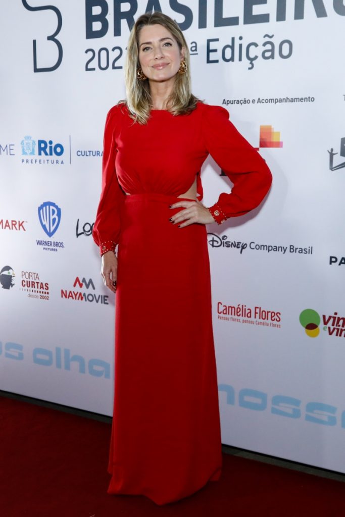Letícia Spiller de vestido vermelho com a mão esquerda  na cintura 