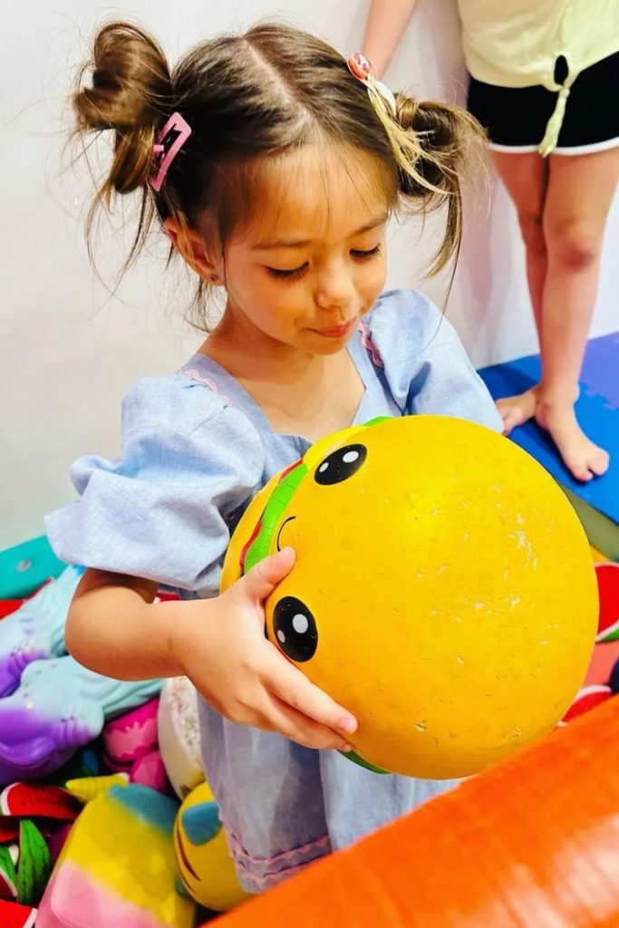 Zoe segurando uma bola amarela 