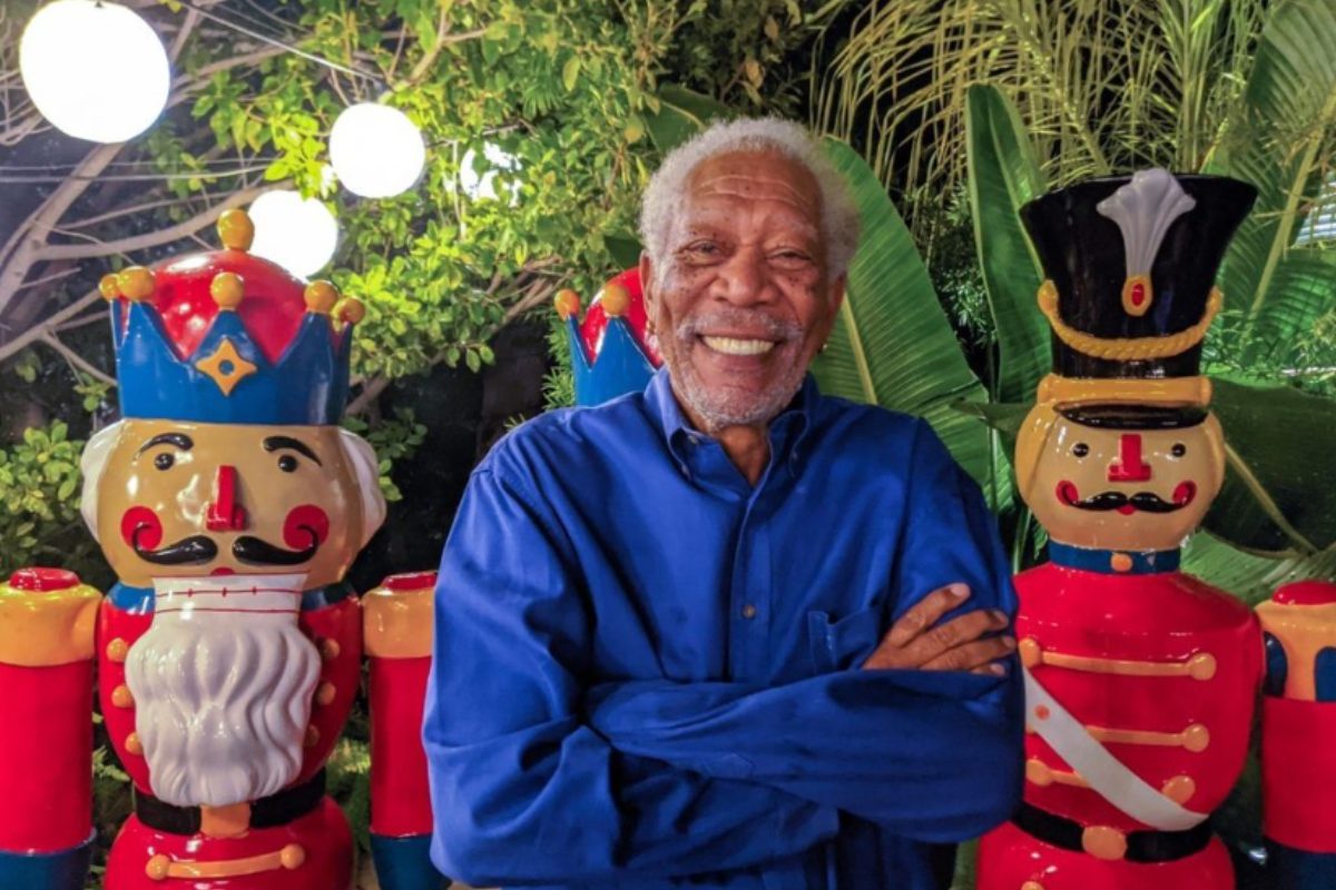 Morgan Freeman de camisa azul, braços cruzados, sorrindo
