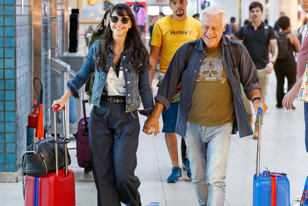 Antônio Fagundes e Alexandra Martins embarcando de mãos dadas no aeroporto Santos Dumont