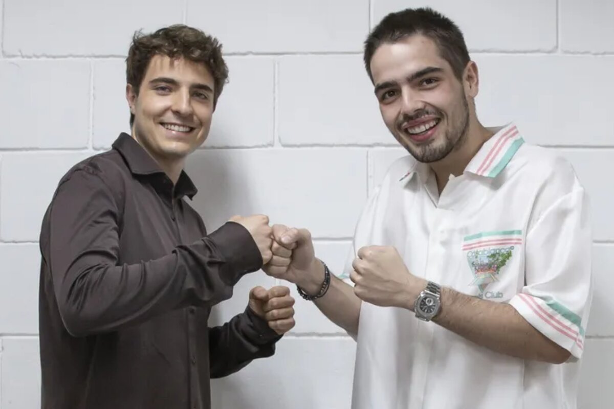 João Augusto Liberato de camisa social marrom, "duelando" com João Guilherme Silva, de camisa branca, ambos sorrindo