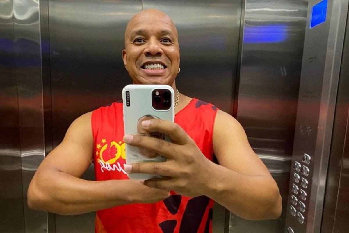 Anderson Leonardo de camisa regata vermelha, sorrindo, fazendo selfie no elevador