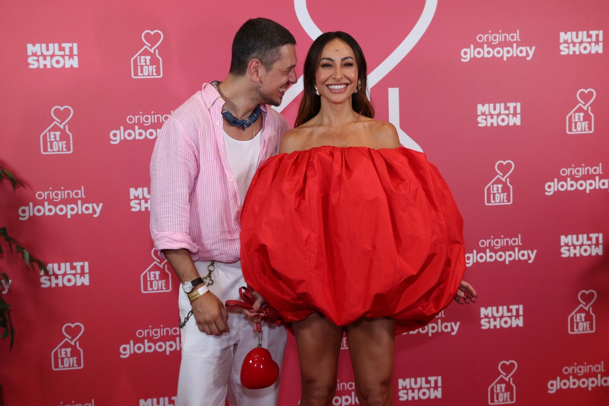 João Vicente de camisa rosa, calça branca, com e Sabrina Sato de vestido vermelho tomara que caia, em forma de coração