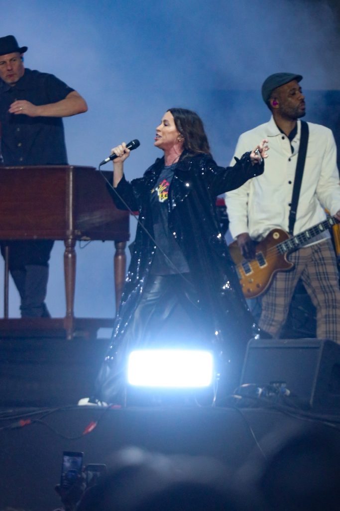 Alanis Morissette cantando no palco do Allianz Parque, em São Paulo, de calça preta e camisa preta 