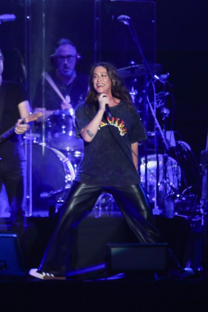 Alanis Morissette cantando no palco do Allianz Parque, em São Paulo, de calça preta e camisa preta 