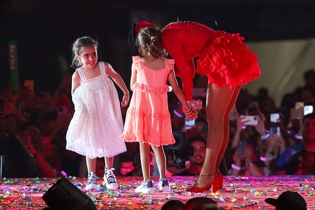 Ivete Sangalo de vermelho com as filhas gêmeas Helena e Marina, no palco 