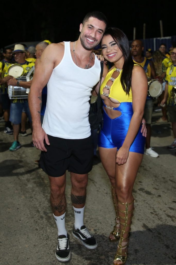 Ricardo Vianna de camiseta branca e bermuda preta abraçado a Lexa, de macaquinho azul e amarelo, no ensaio de rua da Unidos da Tijuca