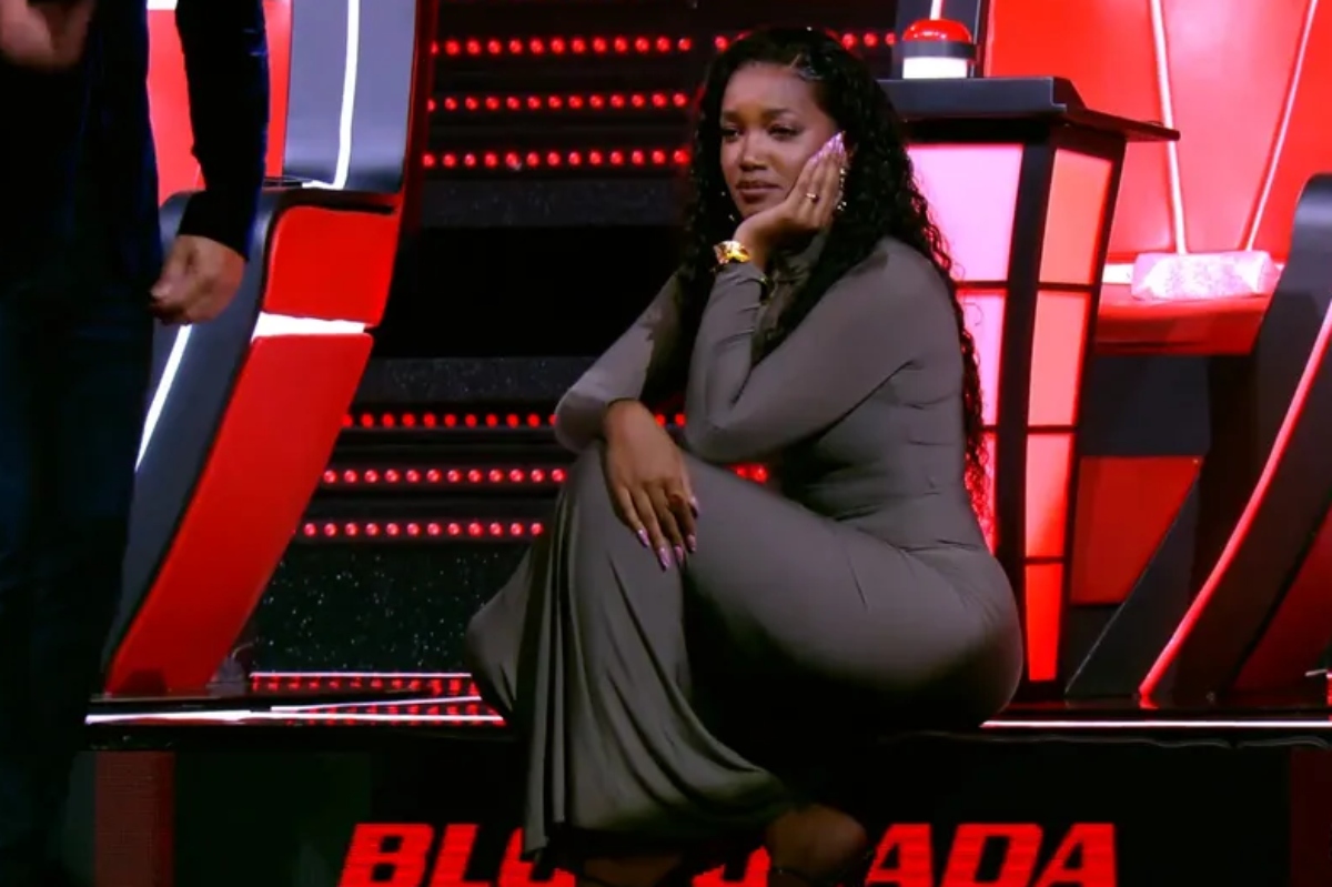 The Voice Brasil - Iza sentada no degrau do palco, com a mão no queixo