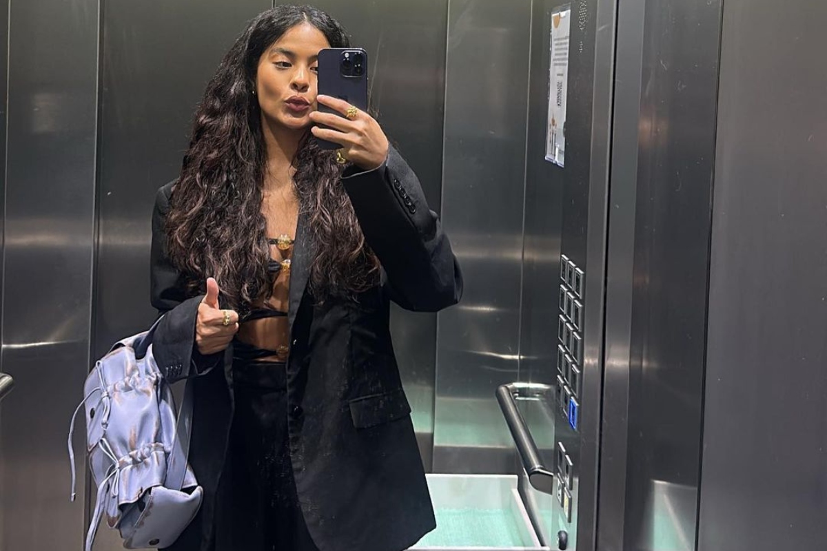 Bella Campos de preto, no elevador, fazendo selfie
